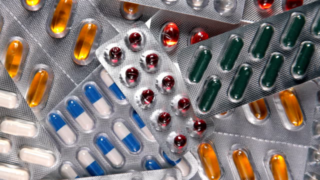 Different pills in a blister pack rotate, close-up 4K
